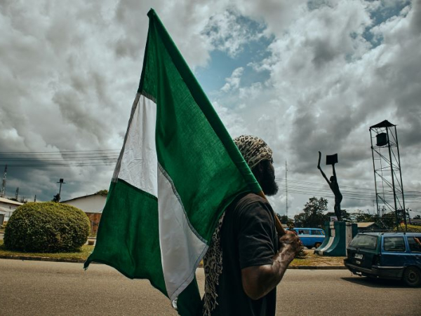 Mężczyzna z flagą Nigerii, za nim plac