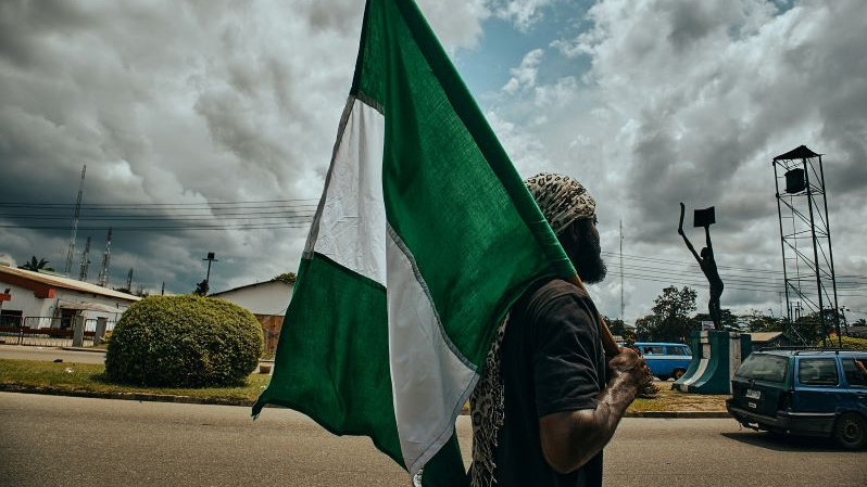 Mężczyzna z flagą Nigerii, za nim plac
